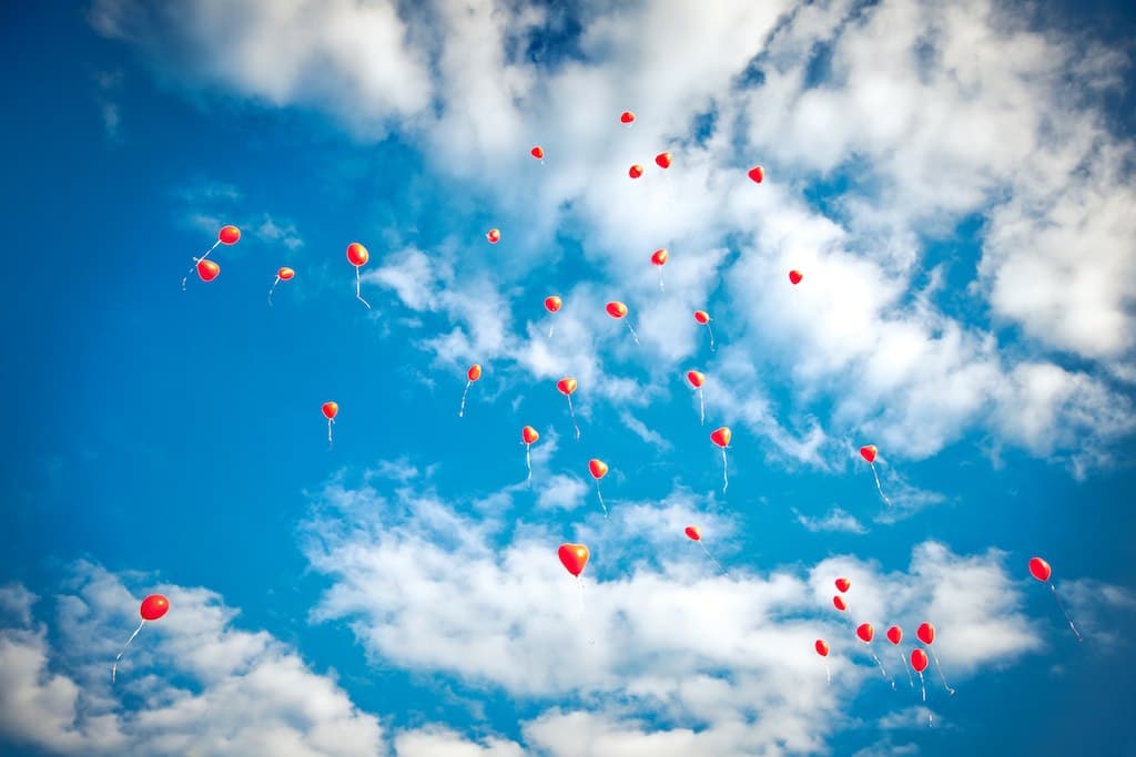 Herzluftballons steigen in den Sommerhimmel